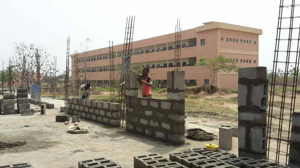 Sullo sfondo la scuola elementare, la prima costruita, in primo piano la scuola superiore in costruzione.