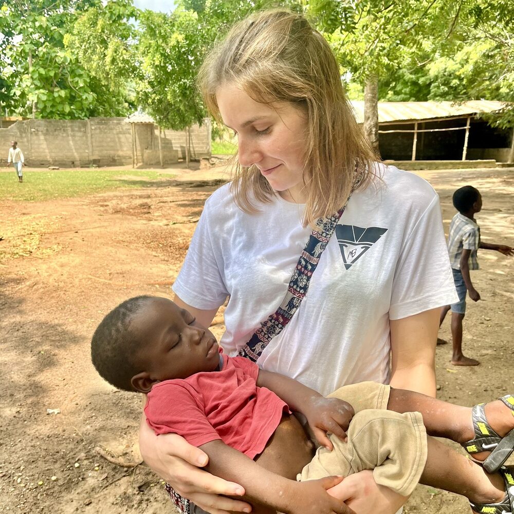 Una volontaria della missione Cuori Grandi Togo che tiene in braccio un bambino addormentato